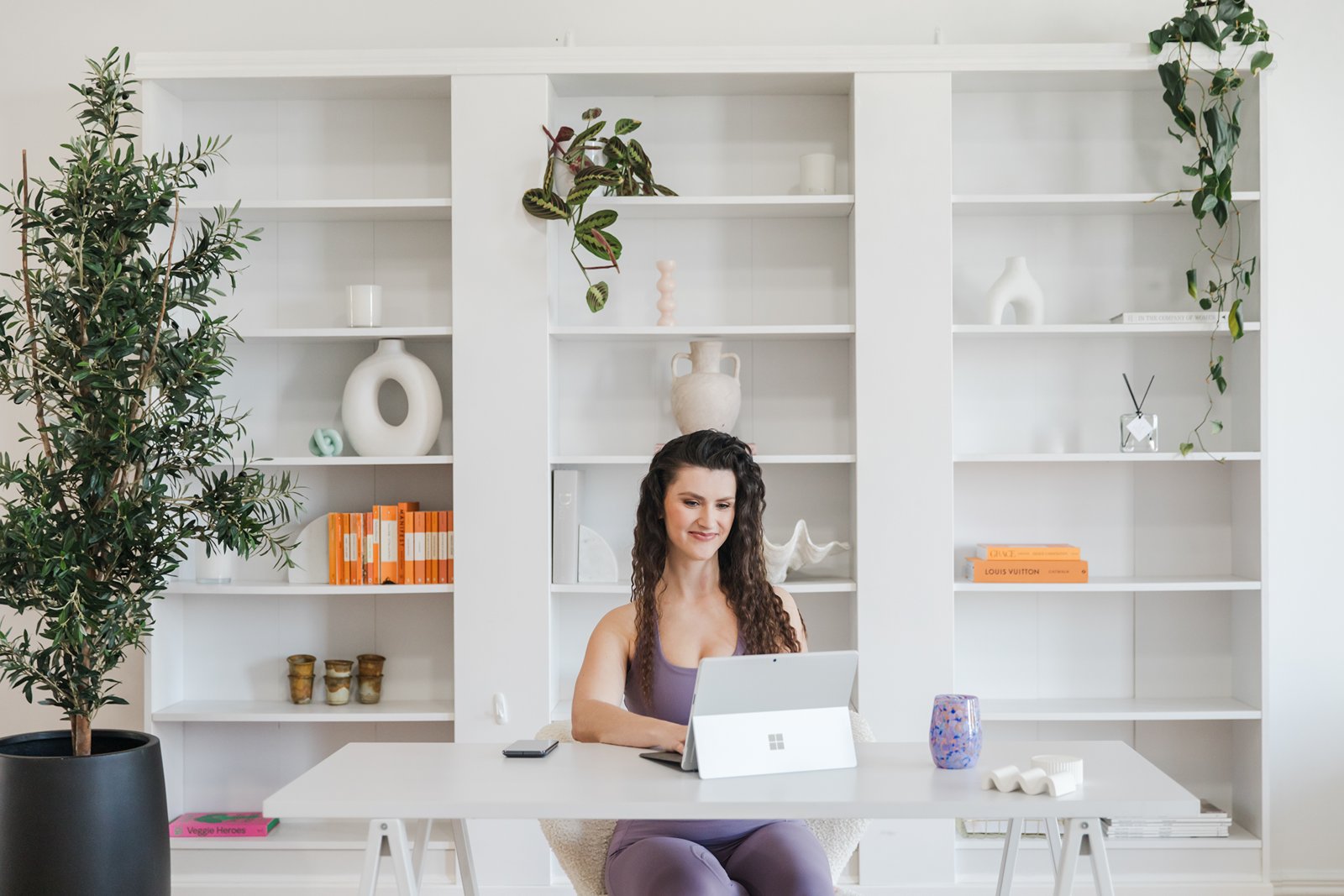 Hailey Ann Co, bookkeeper and somatic Money coach for female entrepreneurs sitting at a desk in an office